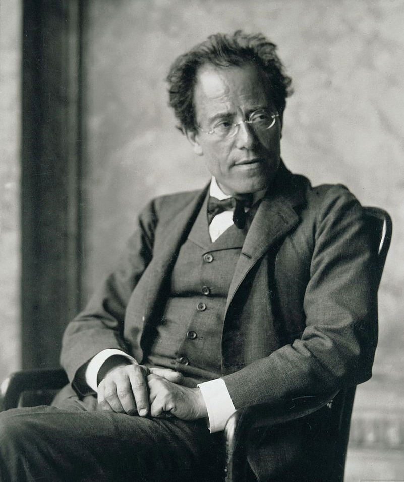 Gustav Mahler sitting in a chair, wearing a three-piece suit and bow tie, with hands folded in his lap