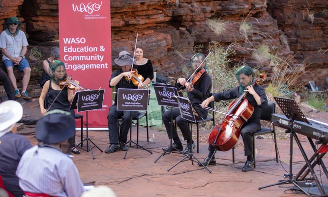 A WASO string quartet performs an outdoor concert among red rock gorges, wearing mosquito head nets.