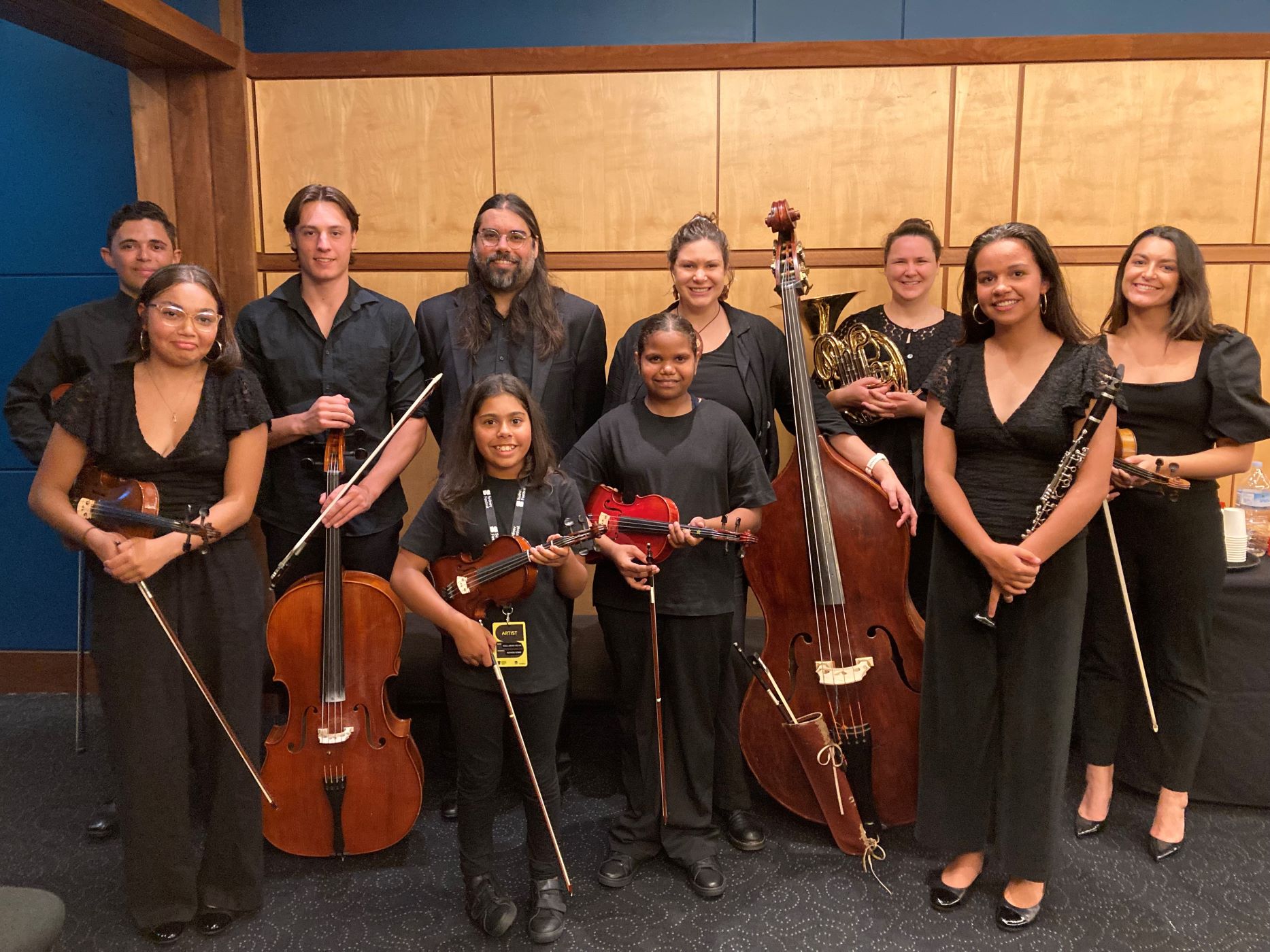 A group of young musicians and their mentors from Short Black Opera, smiling and holding their instruments.