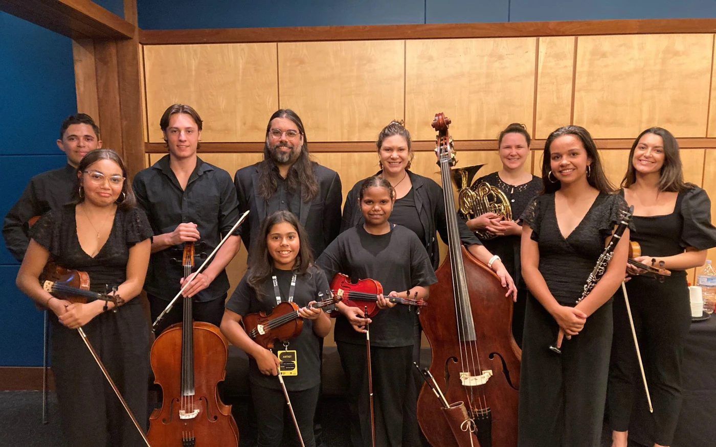 A group of young musicians and their mentors from Short Black Opera, smiling and holding their instruments.