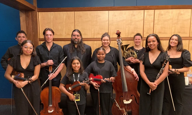 A group of young musicians and their mentors from Short Black Opera, smiling and holding their instruments.
