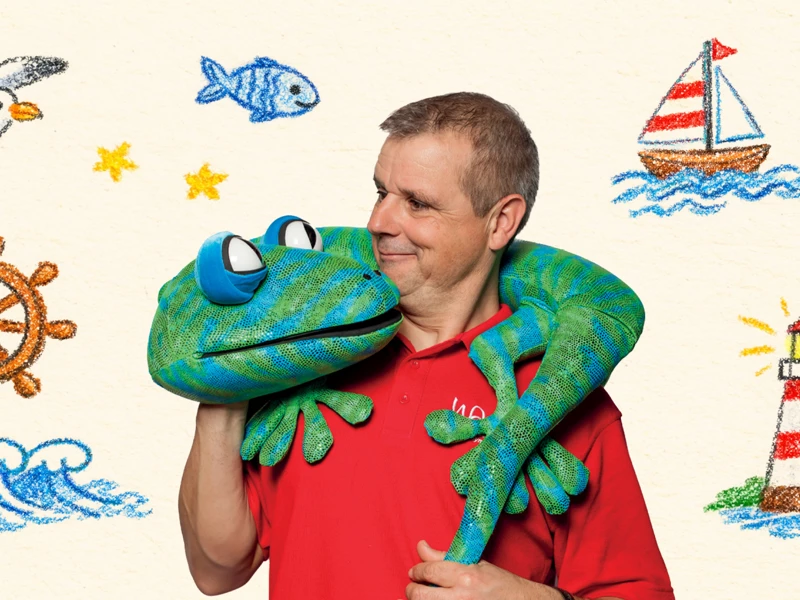 An event banner for Echo the Gecko in which a man holds a lizard puppet and is surrounded by drawings of the seaside