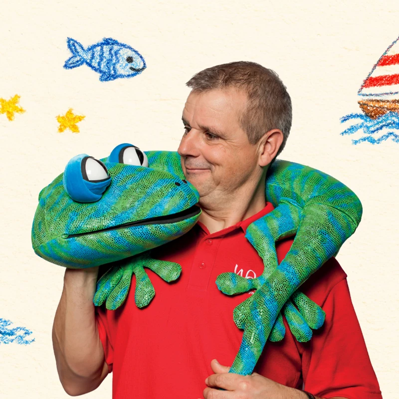 An event banner for Echo the Gecko in which a man holds a lizard puppet and is surrounded by drawings of the seaside