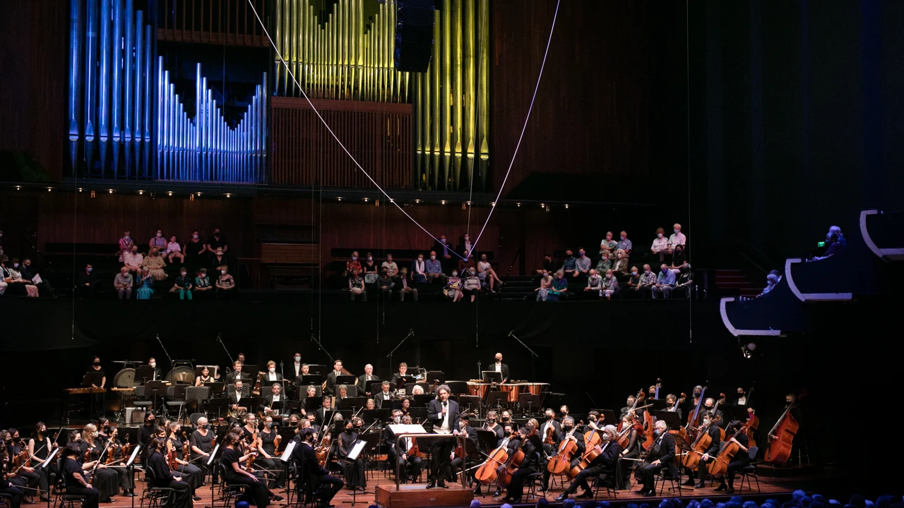 WASO sit on stage as conductor Asher Fisch addresses audience at Perth Concert Hall.