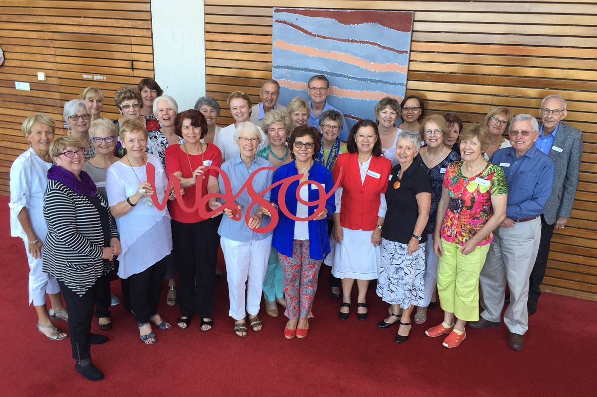 A large group of volunteers smile for a group photo, with those at the front holding a red WASO sign.