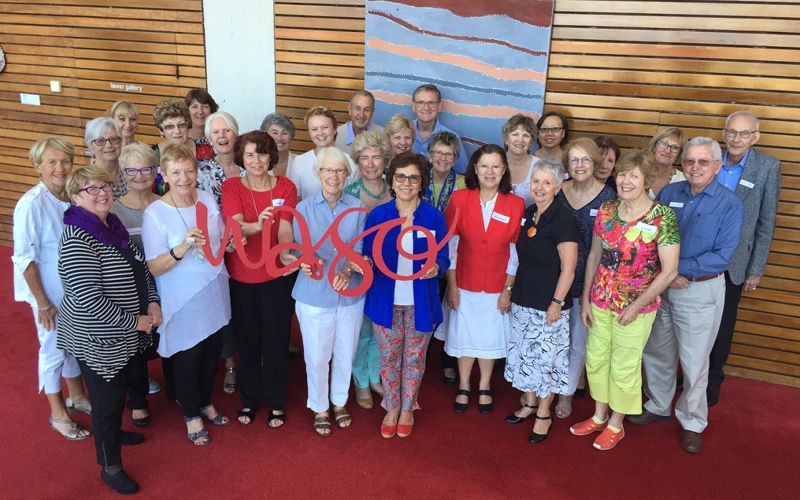 A large group of volunteers smile for a group photo, with those at the front holding a red WASO sign.
