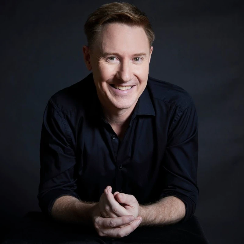 Headshot of Benjamin Northey wearing a black collared shirt.