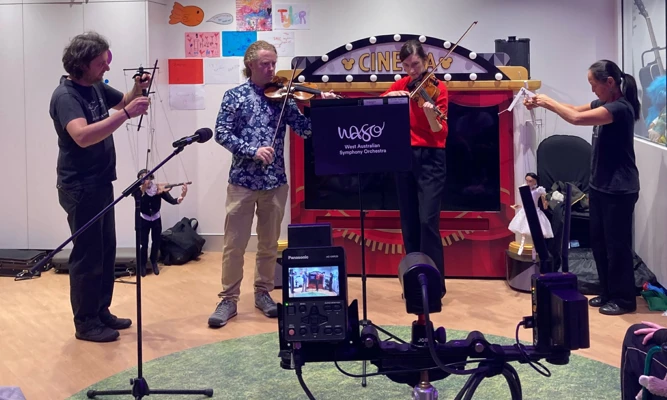WASO violinists Zak Rowntree and Stephanie Dean perform with two marionette puppets as part of the Hospital Orchestra Project.