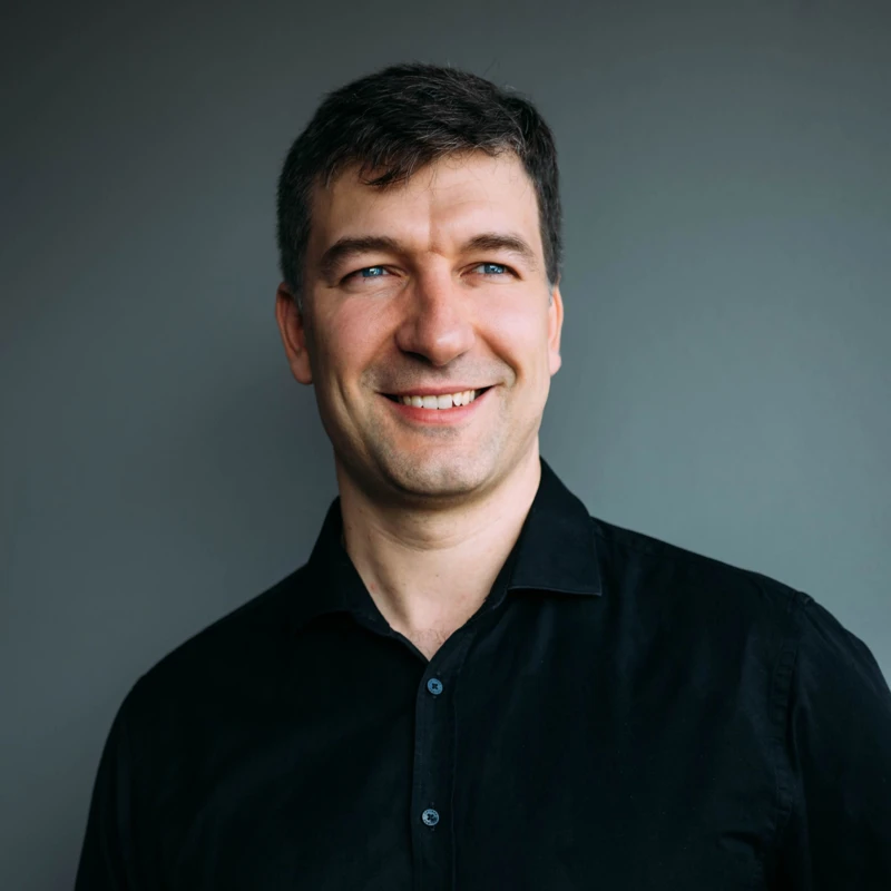 Headshot of Konstantin Shamray wearing a black collared shirt.