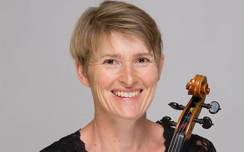 Headshot of Kierstan Arkleysmith wearing a black lace top, holding a viola.