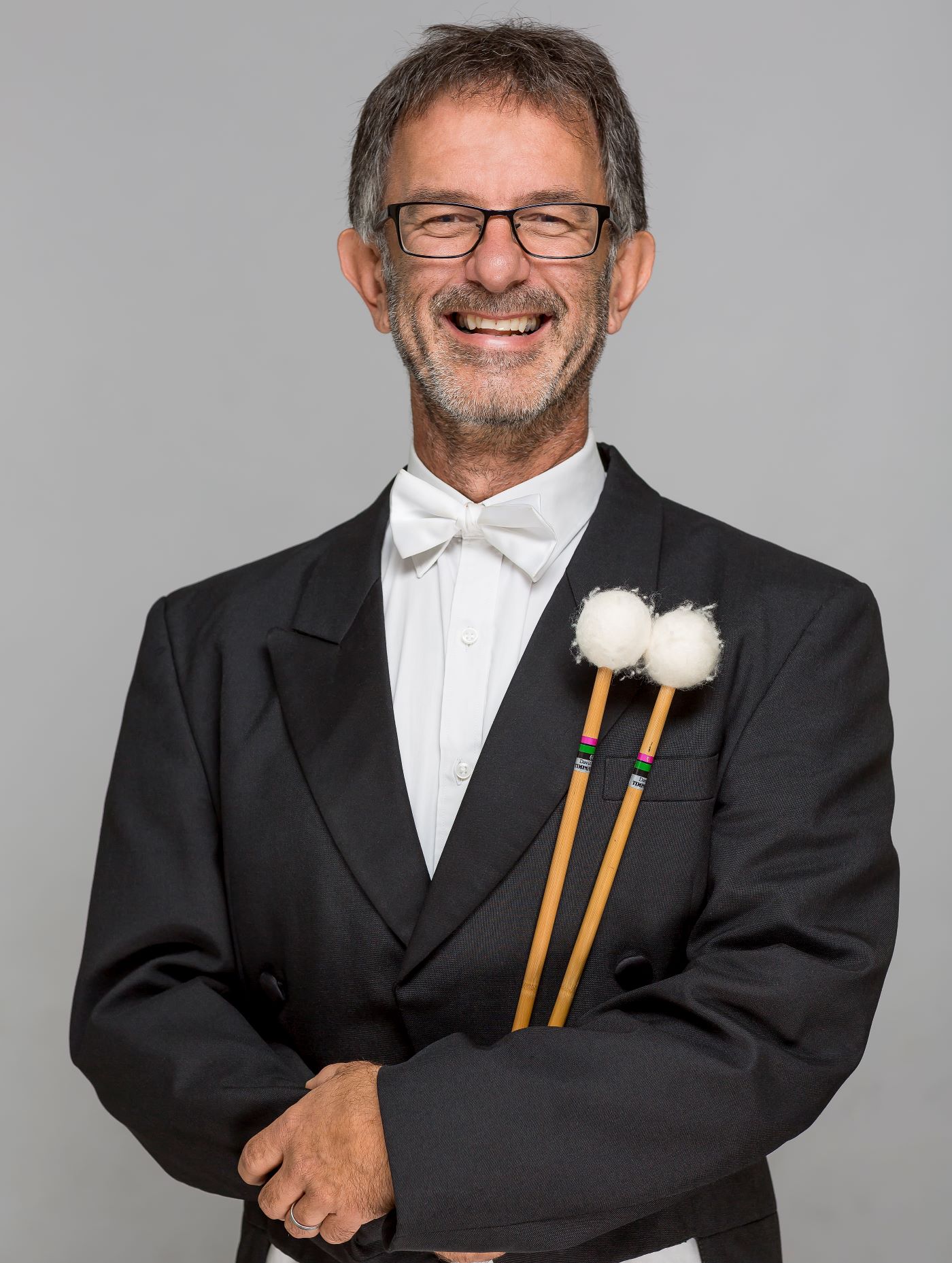 Headshot of Alex Timcke wearing a formal suit, holding timpani mallets.
