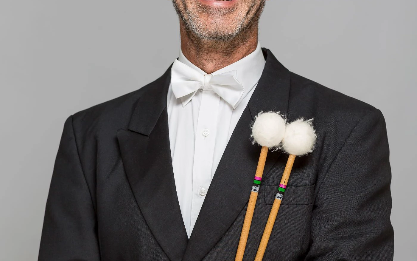 Headshot of Alex Timcke wearing a formal suit, holding timpani mallets.