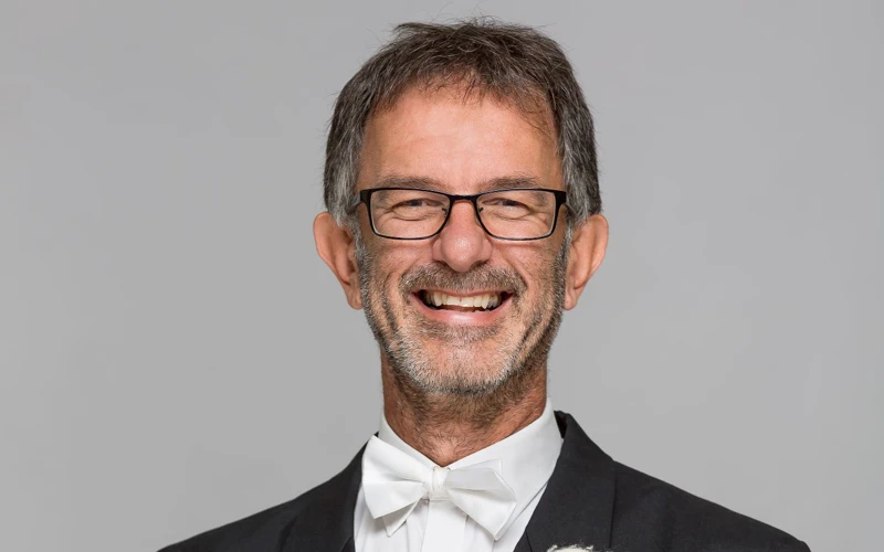 Headshot of Alex Timcke wearing a formal suit, holding timpani mallets.