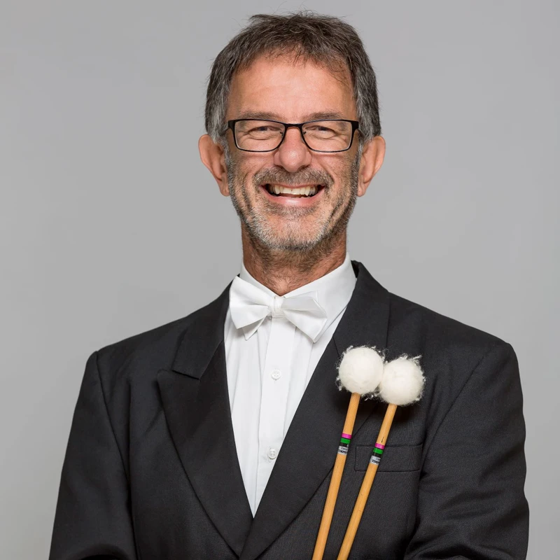 Headshot of Alex Timcke wearing a formal suit, holding timpani mallets.