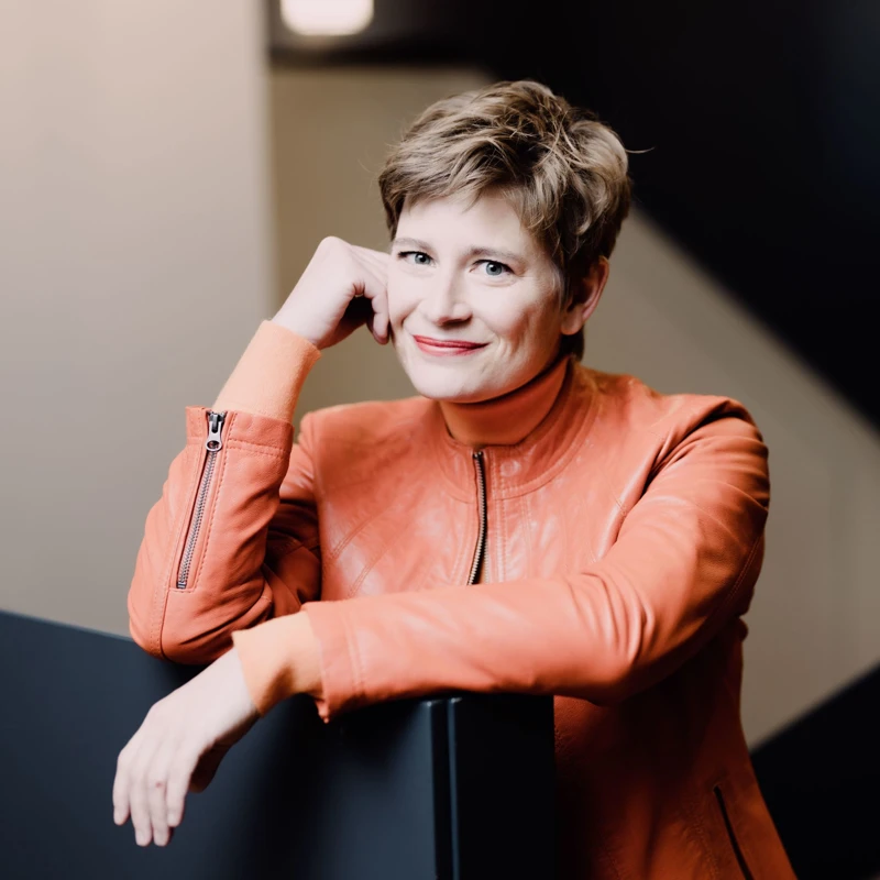 Headshot of Anja Bihlmaier wearing a leather orange biker jacket.
