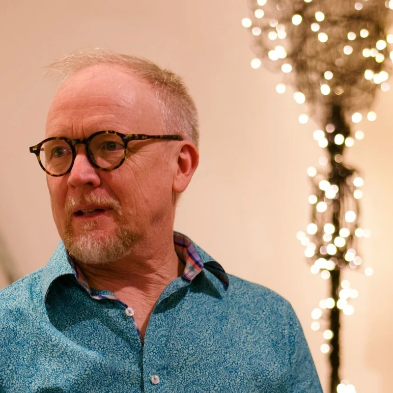 Headshot of James Ledger wearing a blue collared shirt and tortoise shell glasses.