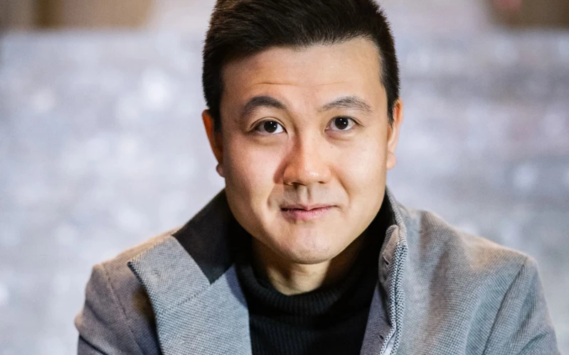 Headshot of Thaddeus Huang wearing a grey jacket and black shirt.