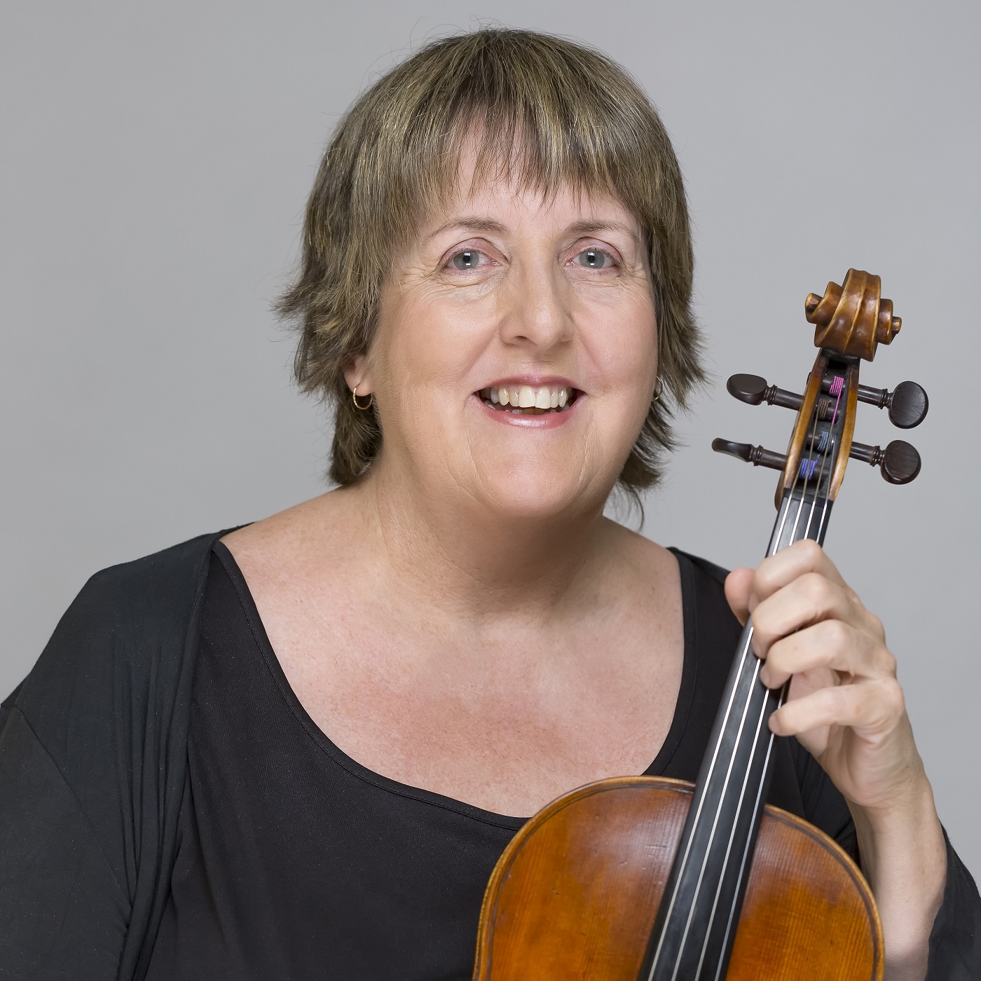 Headshot of Helen Tuckey wearing a black top, holding a viola.