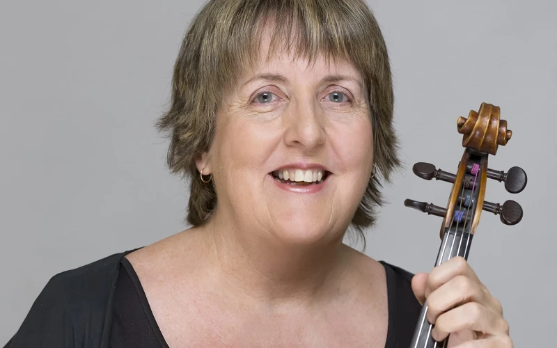 Headshot of Helen Tuckey wearing a black top, holding a viola.