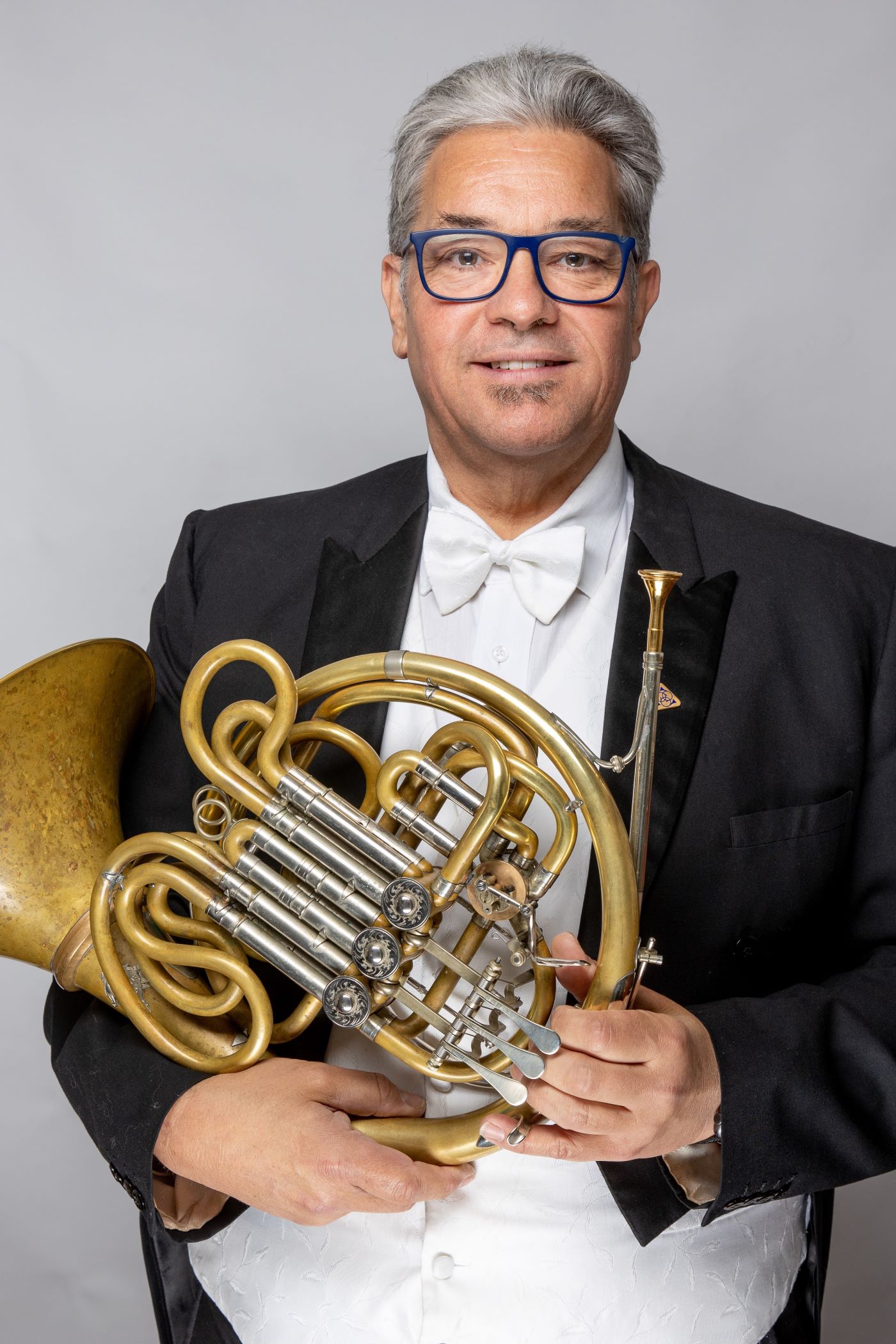 Headshot of Rob Gladstones wearing a formal suit, holding a horn.