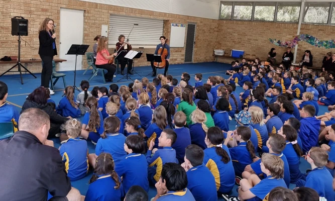 A large group of primary school students watch a WASO string quartet perform in their school gym.