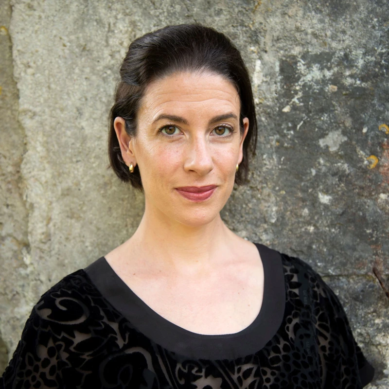 Headshot of Sara Duhig wearing a patterned sheer black top.