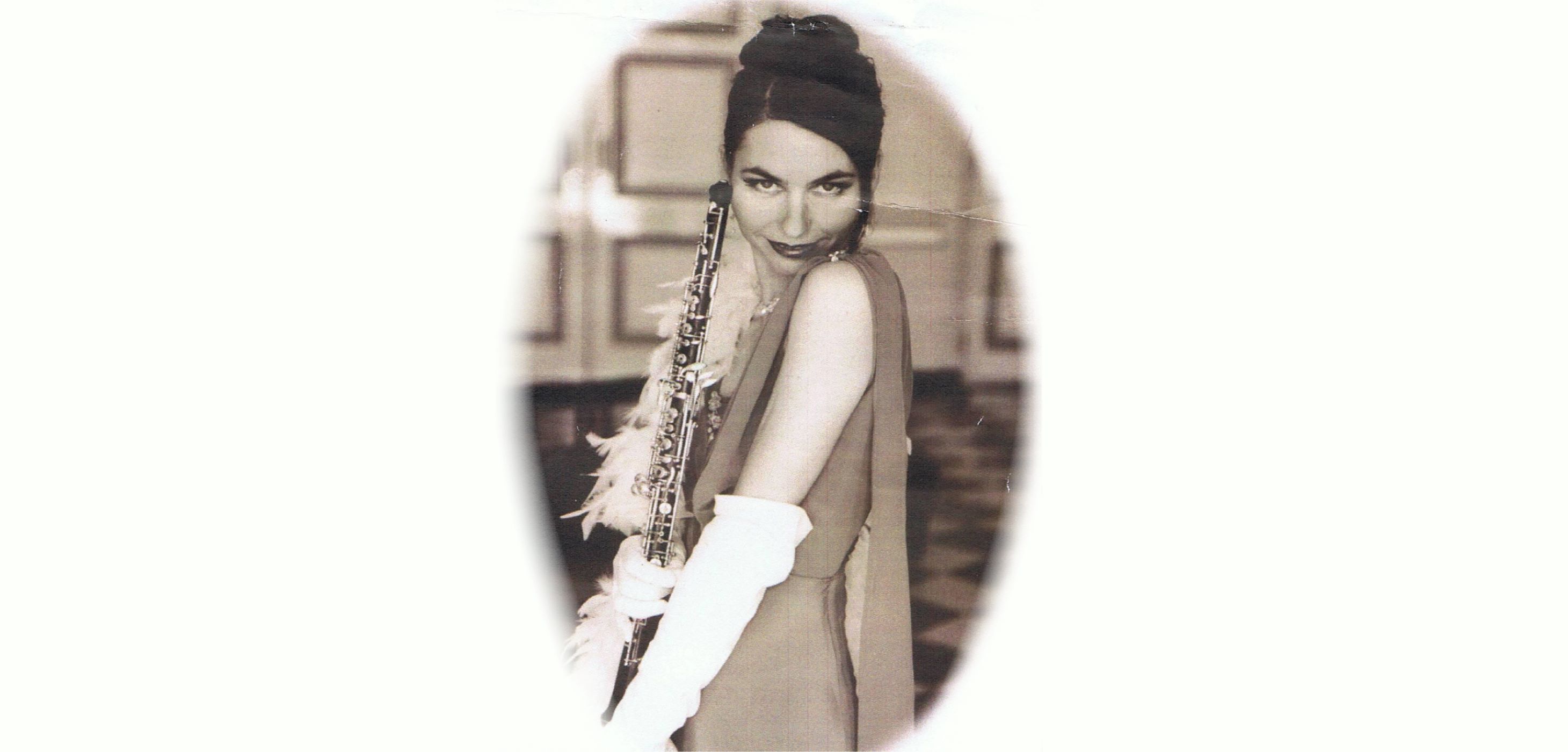 Vintage portrait of Leanne Glover wearing an evening gown, gloves and feather boa, holding an oboe.