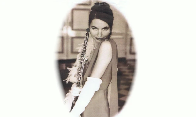 Vintage portrait of Leanne Glover wearing an evening gown, gloves and feather boa, holding an oboe.