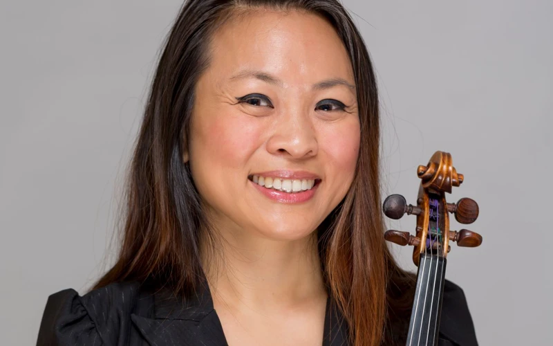 Headshot of Semra Lee wearing a black top, holding a violin.