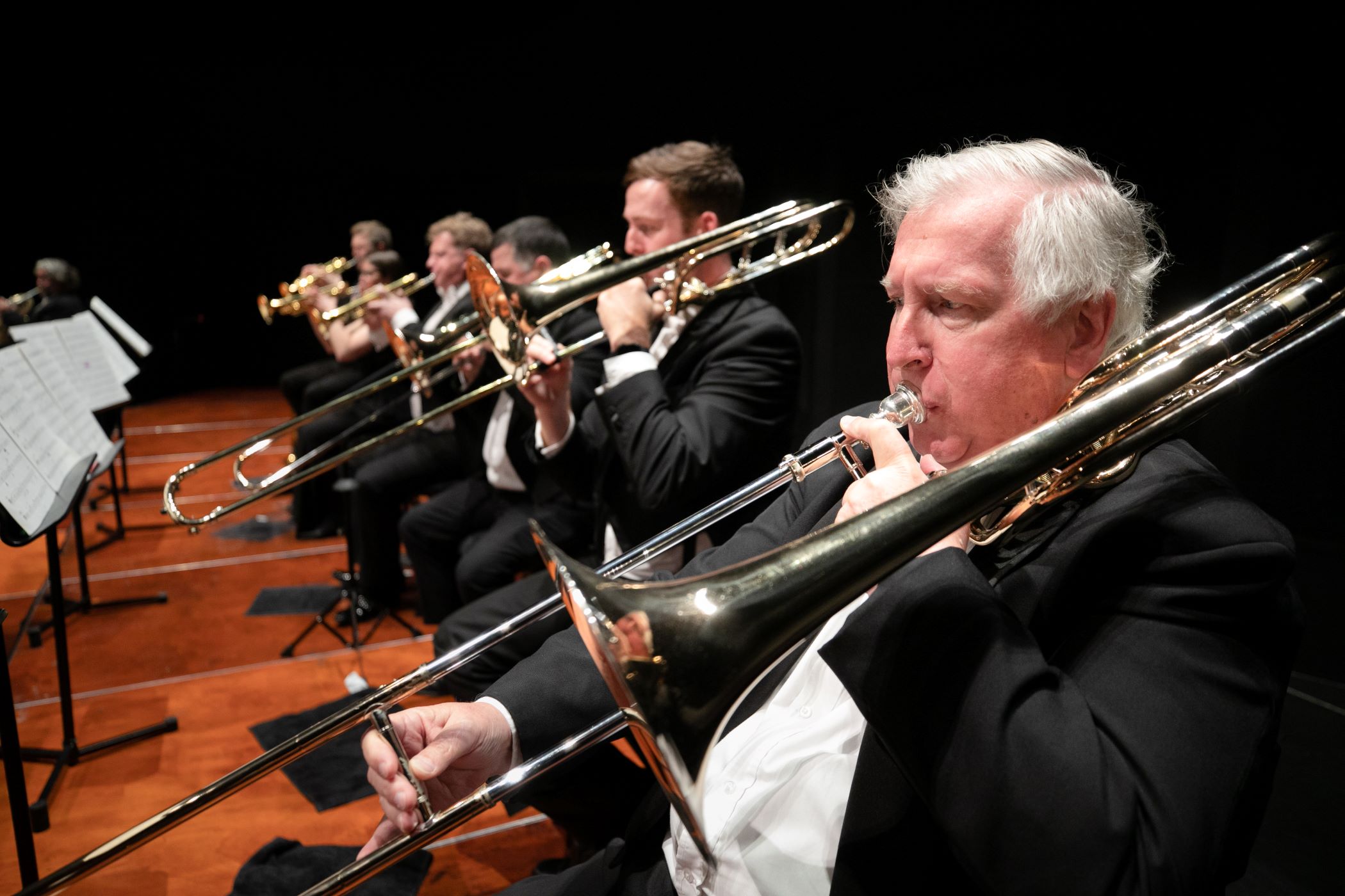 Trombone players perform together on stage during an orchestral concert.